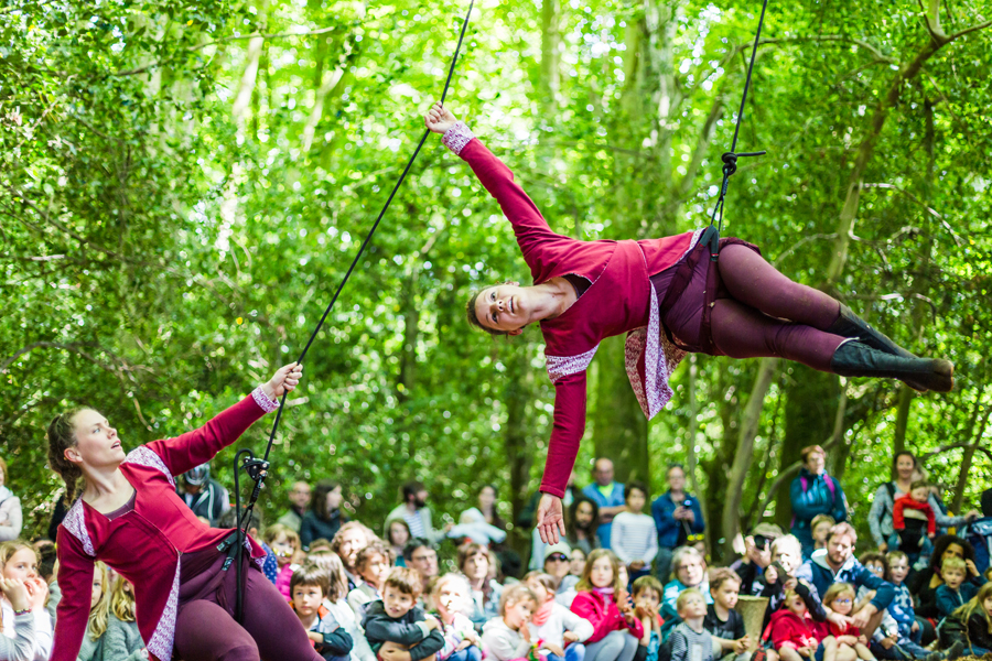 deux danseuses l'une au sol tenant une corde et l'autre suspendue parallèle au sol dans un environnement naturel