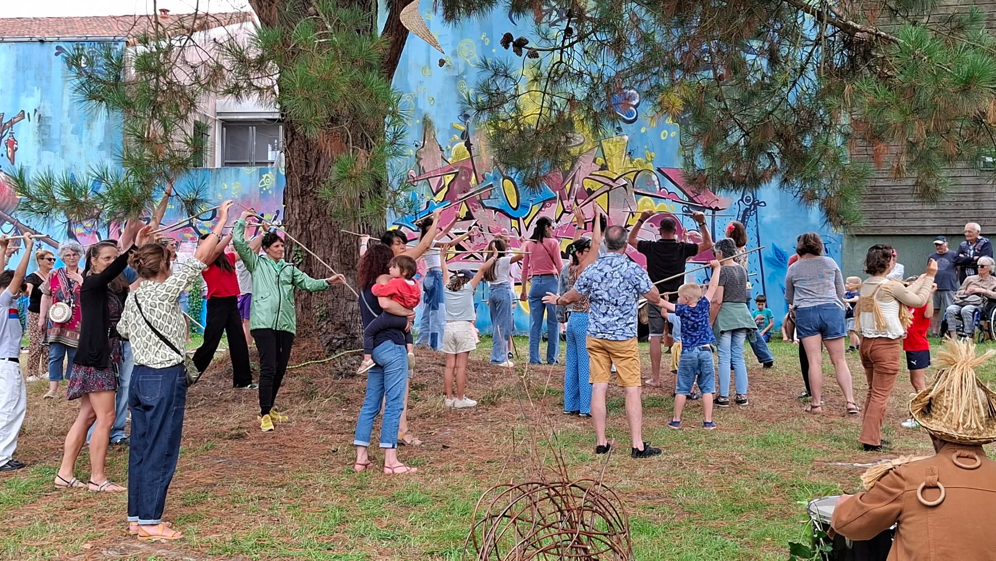 un public de spectacle participatif dansant avec les artistes au pied d'un cèdre